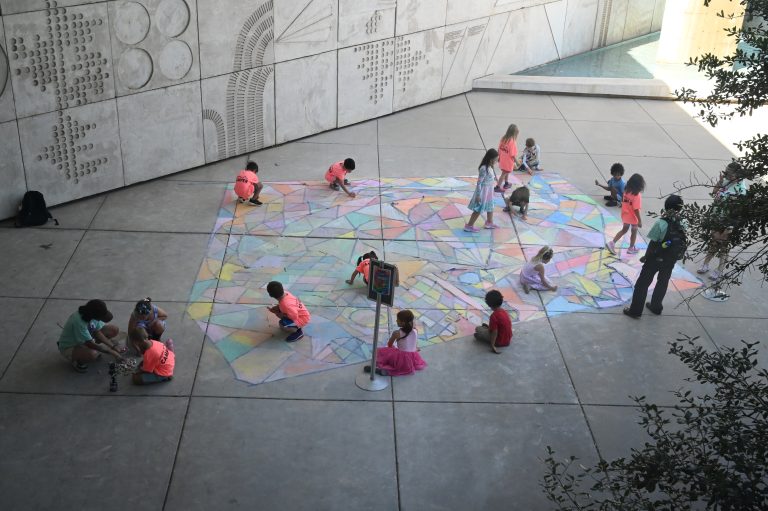 kids using chalk to color in an outside mural