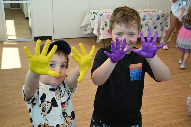two kids smiling with paint on their hands