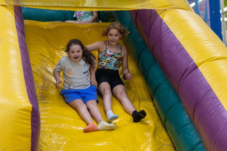 two kids smiling on a bounce slide