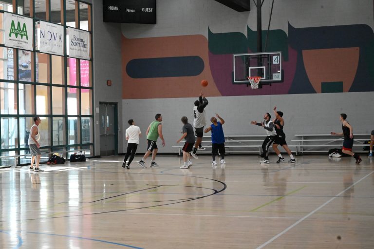 nine men playing basketball in an indoor gymnasium