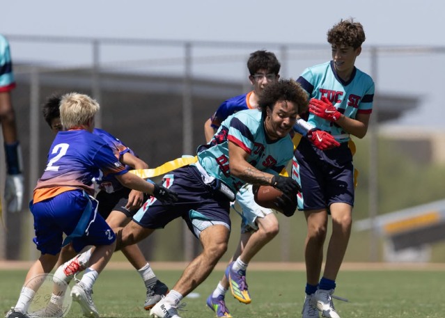 Group of teenage boys playing flag football outside on a field