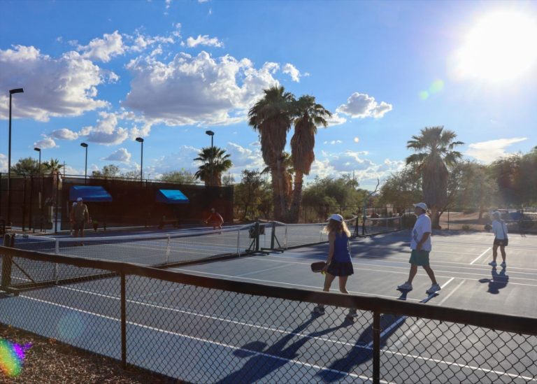 adults play pickleball outside on a pickleball court