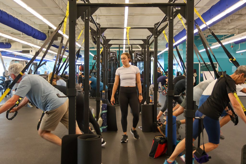 adults exercise on large doorframe-like equipment