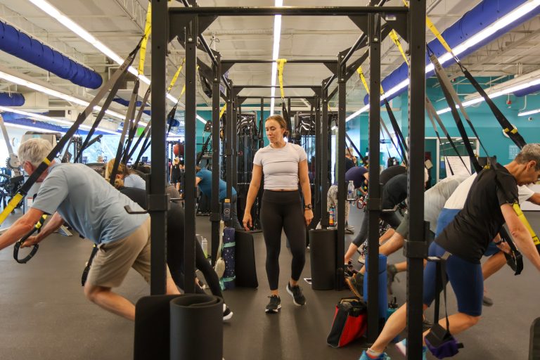 adults exercise on large doorframe-like equipment