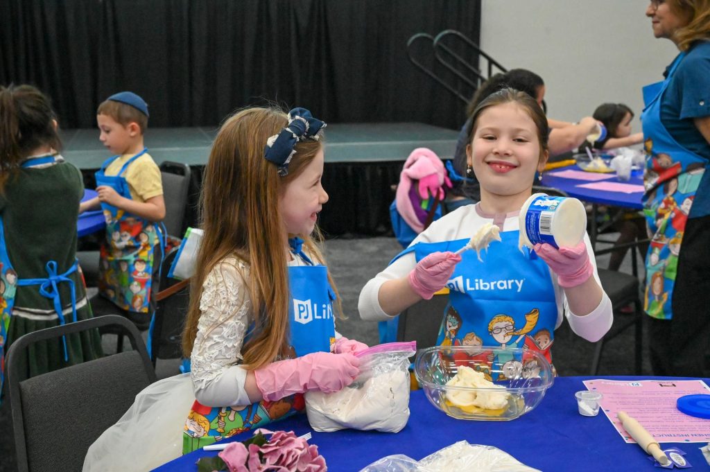 two kids stand behind a table smiling